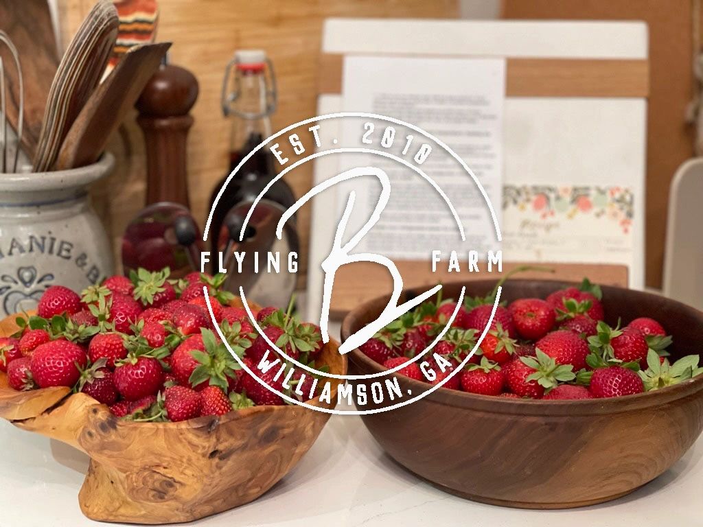 Flying B Farm provisions logo over fresh strawberries